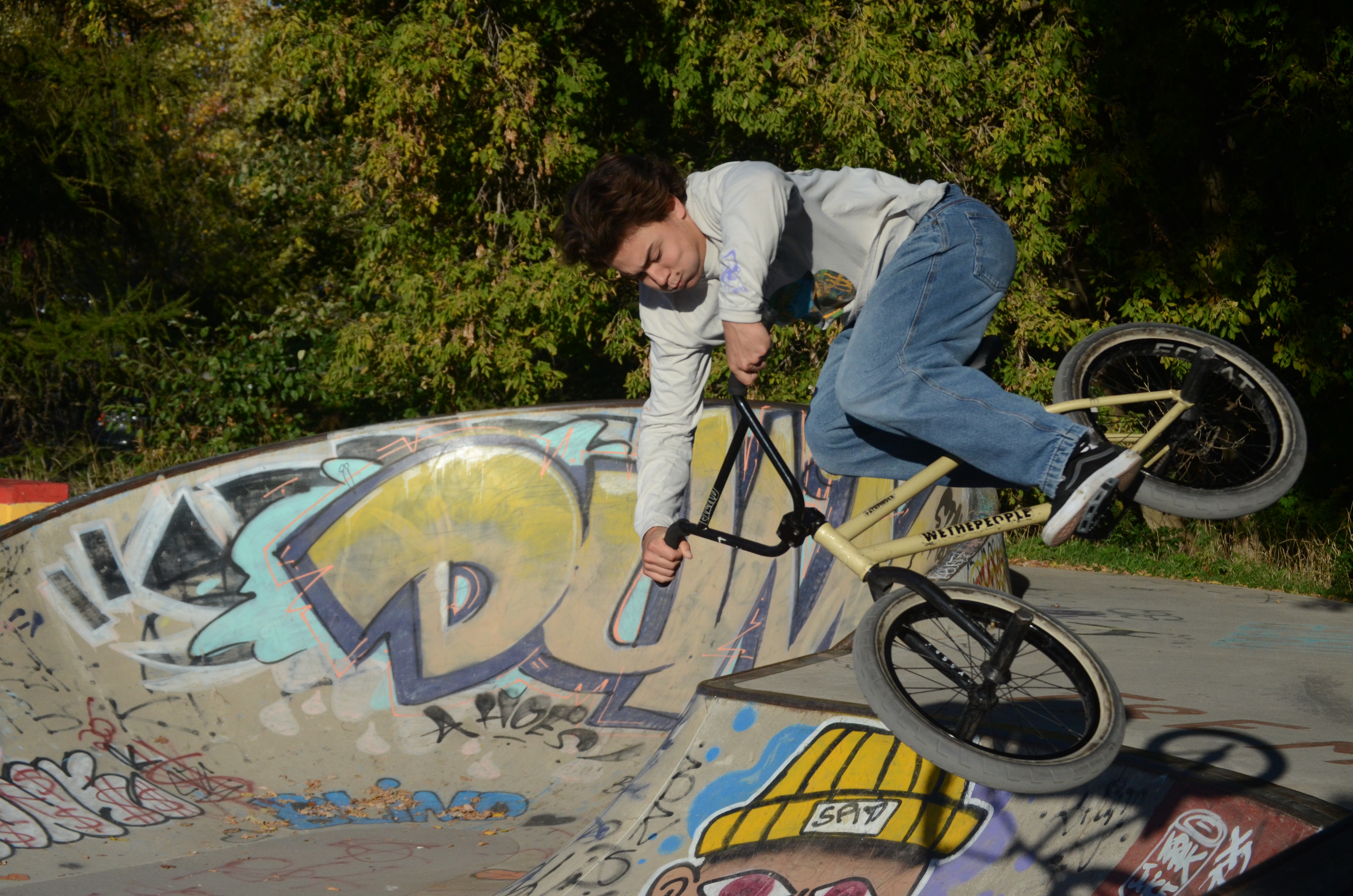 Dark-haired man jumping a ramp at the skatepark on a BMX bike.