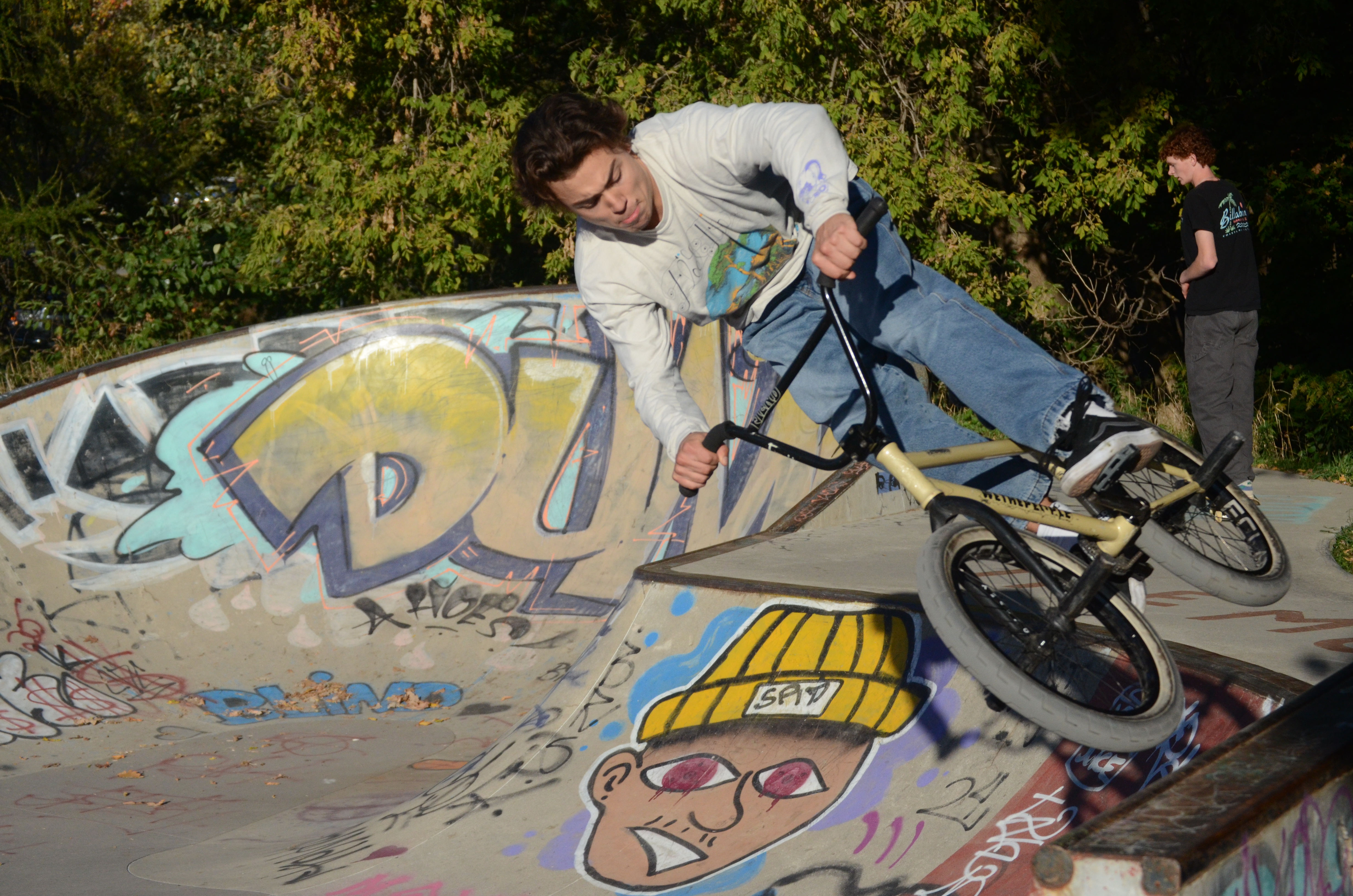 Dark-haired man jumping a ramp at the skatepark on a BMX bike.