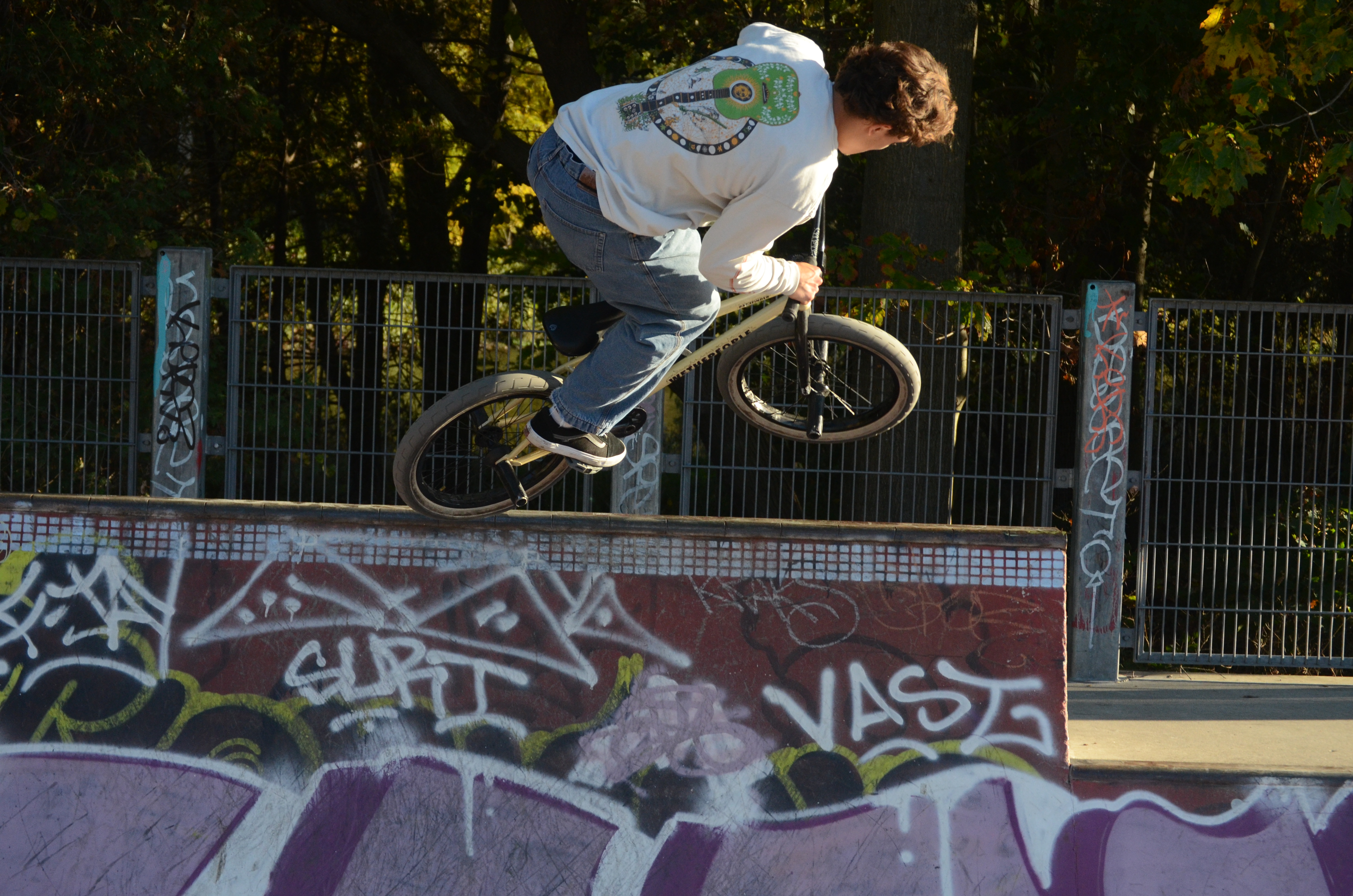 Dark-haired man jumping a ramp at the skatepark on a BMX bike.