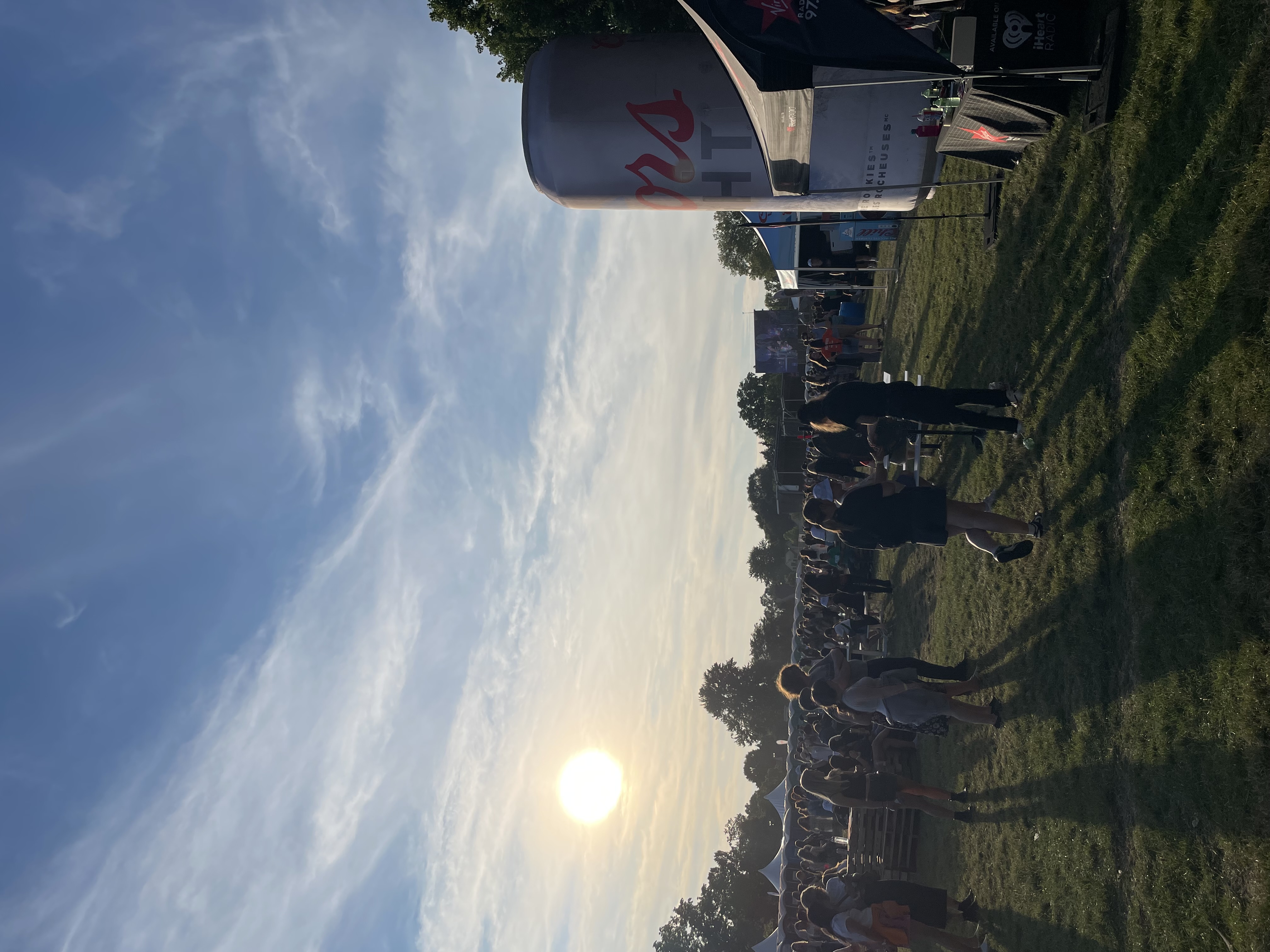 A low sun starting to set over a field of people at a music festival.