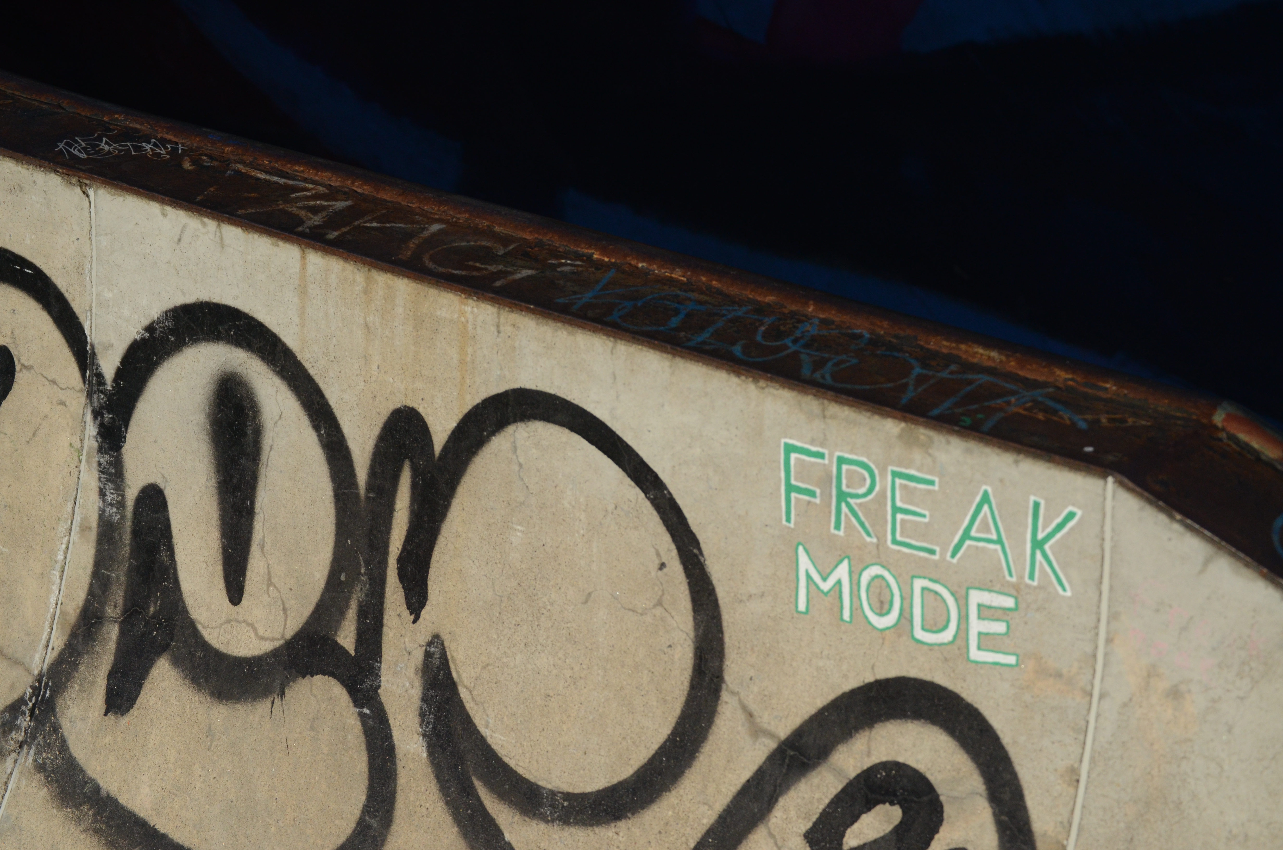 Graffiti on a cement block at a skatepark reading 'FREAK MODE'.