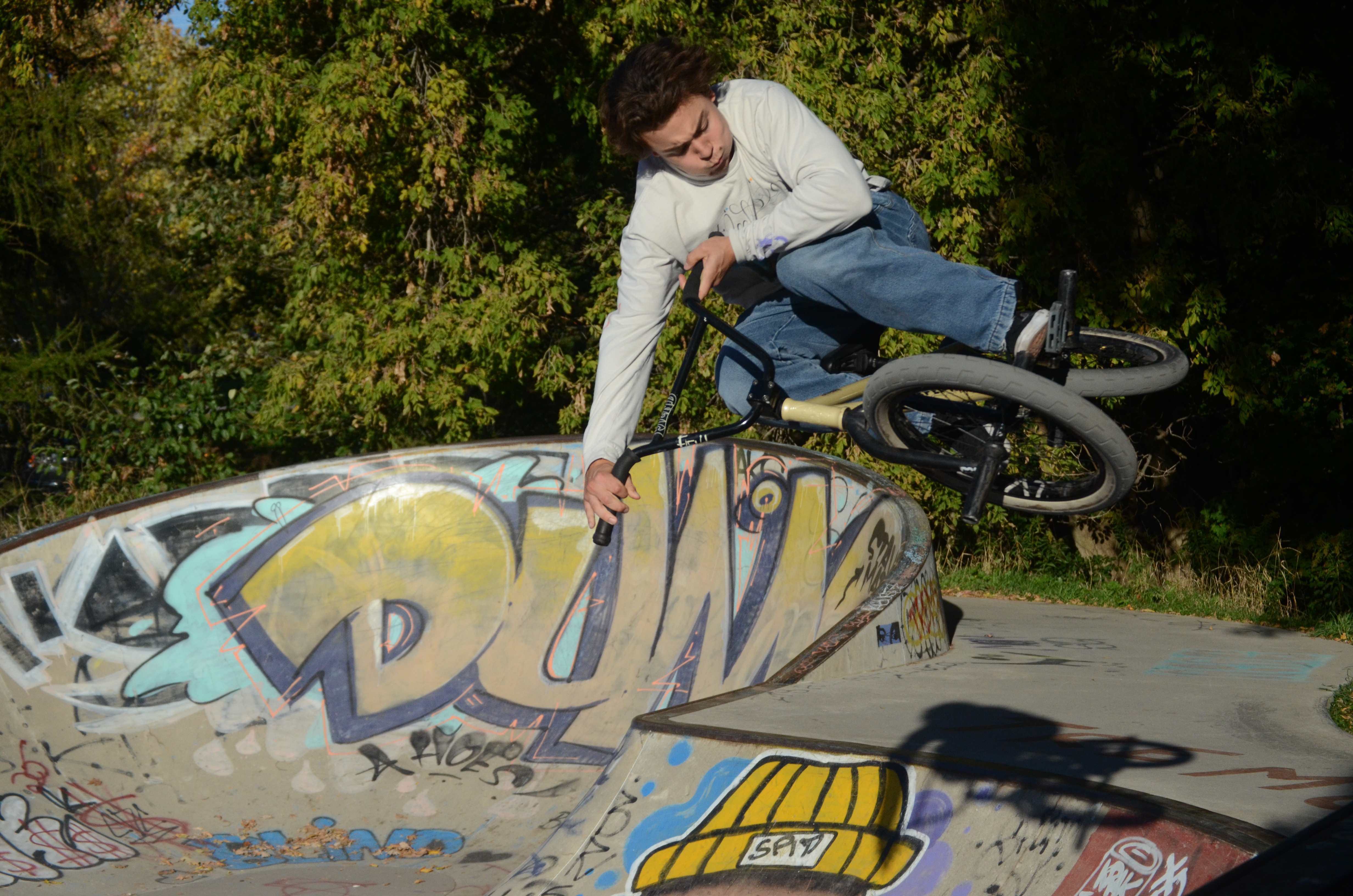 Dark-haired man jumping a ramp at the skatepark on a BMX bike.